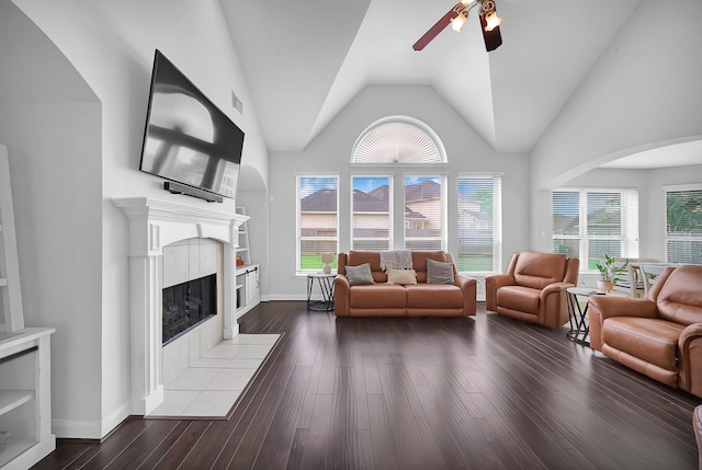 living room with ceiling fan, high vaulted ceiling, a tile fireplace, and wood-type flooring