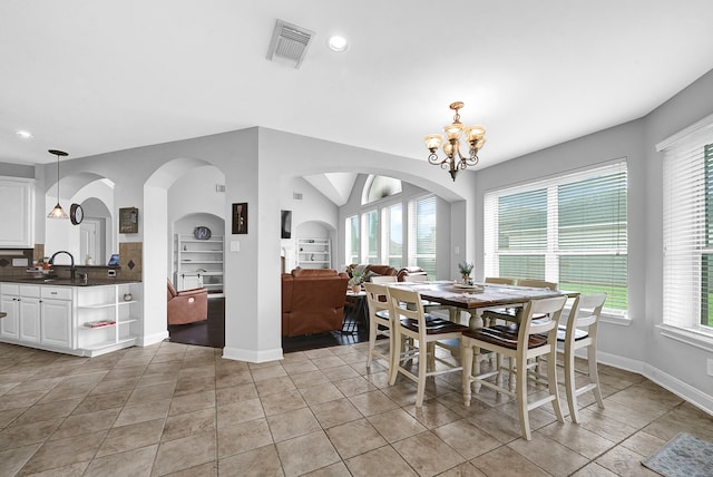 dining area featuring built in features, a notable chandelier, sink, and light tile patterned flooring