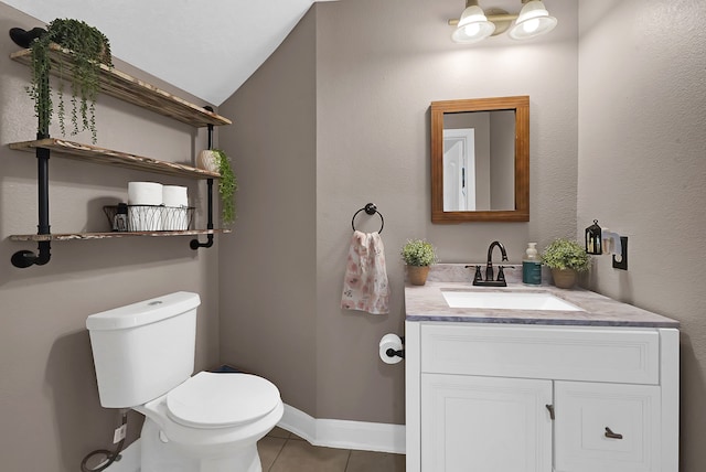 bathroom featuring tile patterned flooring, toilet, vaulted ceiling, and vanity