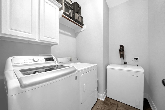 laundry room featuring dark tile patterned floors, cabinets, and washer and dryer