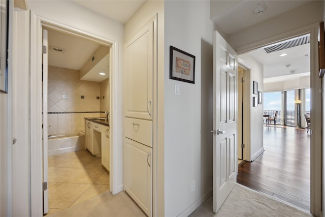 hall featuring sink and light tile patterned floors