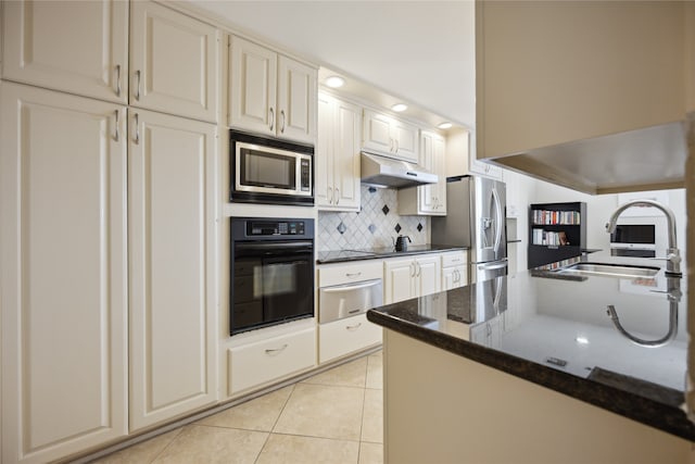 kitchen with backsplash, stainless steel appliances, sink, light tile patterned floors, and dark stone counters