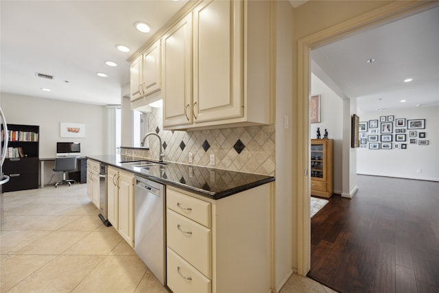 kitchen featuring light wood-type flooring, decorative backsplash, stainless steel dishwasher, cream cabinetry, and sink