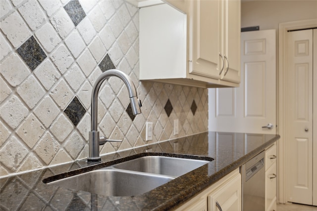 kitchen with dishwasher, decorative backsplash, sink, cream cabinetry, and dark stone countertops