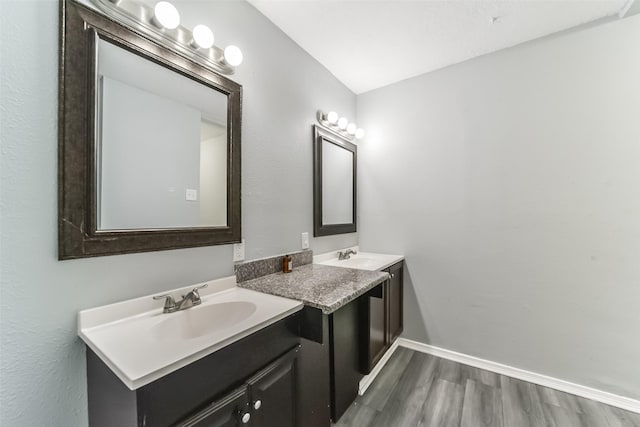 bathroom featuring double vanity, a sink, baseboards, and wood finished floors