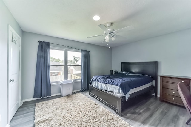 bedroom with ceiling fan, wood finished floors, and baseboards