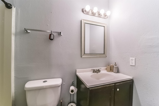 bathroom featuring a textured wall, vanity, and toilet