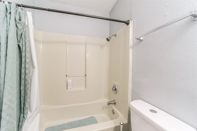 bathroom featuring a textured wall, toilet, and shower / bathtub combination with curtain