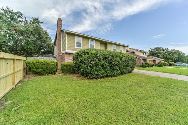 view of front of home featuring brick siding, fence, a chimney, and a front lawn