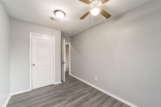 unfurnished bedroom with visible vents, baseboards, ceiling fan, wood finished floors, and a textured ceiling