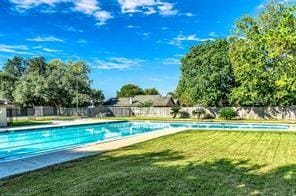 community pool featuring a yard and fence