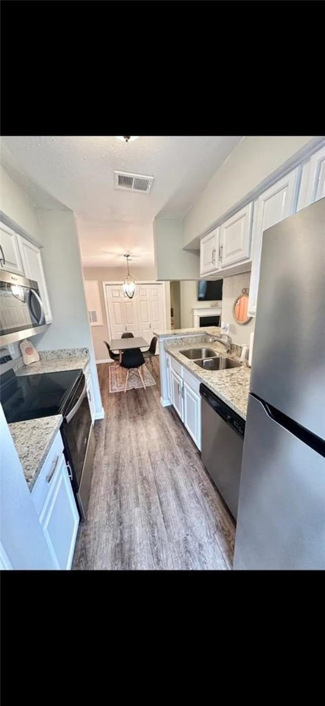 kitchen with stainless steel appliances, a sink, visible vents, white cabinets, and light countertops