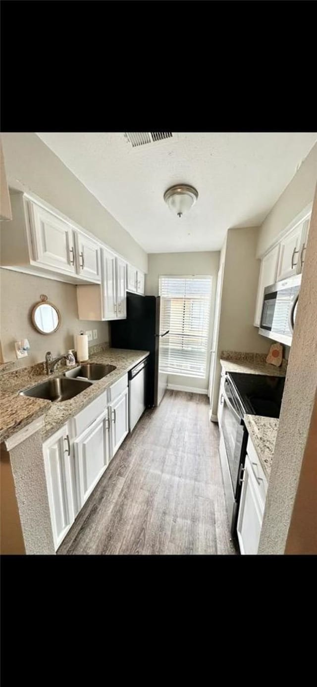 kitchen with stainless steel appliances, light countertops, white cabinets, and a sink