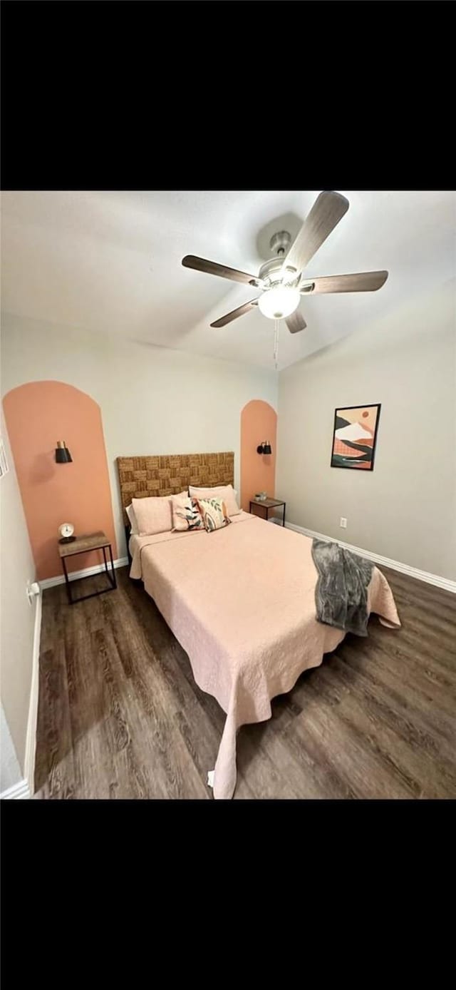 bedroom featuring baseboards, arched walkways, ceiling fan, and wood finished floors