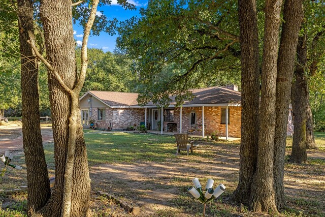 130 Green Acres Loop, Bastrop, TX 78602 - ranch-style house featuring brick siding, covered porch, and a front yard