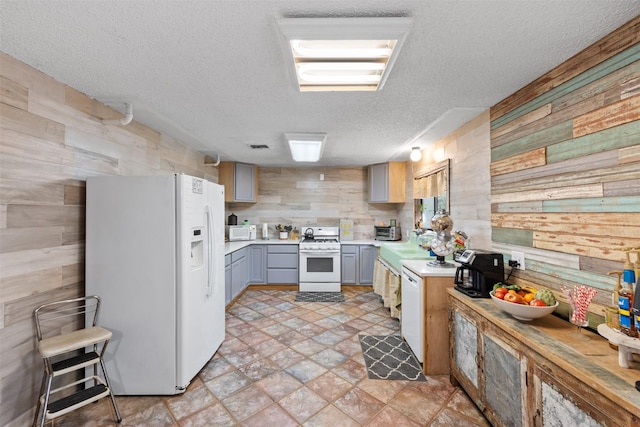 130 Green Acres Loop, Bastrop, TX 78602 - kitchen featuring light countertops, wood walls, gray cabinetry, and white appliances