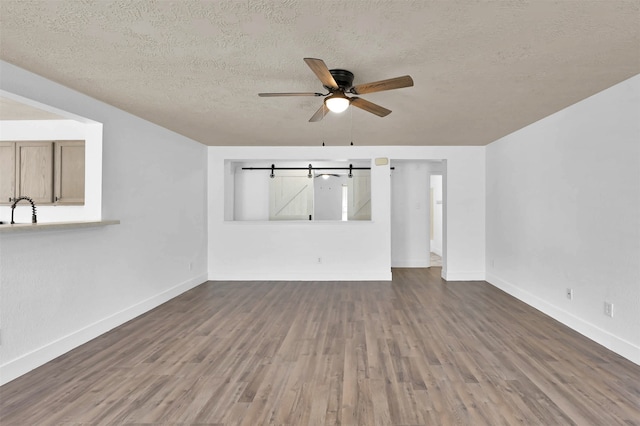 empty room with a textured ceiling, ceiling fan, hardwood / wood-style floors, and sink