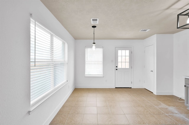 unfurnished dining area featuring a textured ceiling and light tile patterned flooring