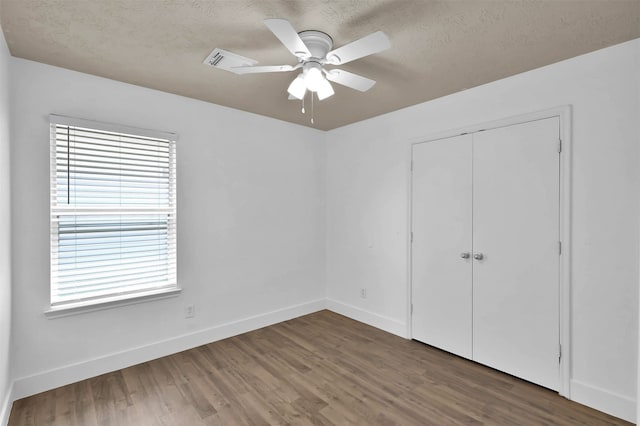 unfurnished bedroom with ceiling fan, wood-type flooring, a closet, and a textured ceiling