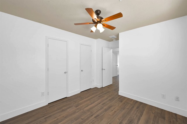 unfurnished bedroom featuring hardwood / wood-style flooring, multiple closets, and ceiling fan