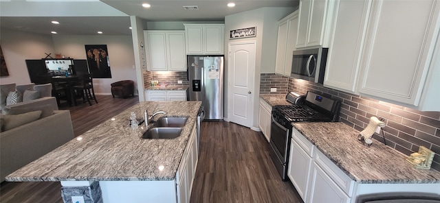 kitchen featuring appliances with stainless steel finishes, an island with sink, sink, and tasteful backsplash