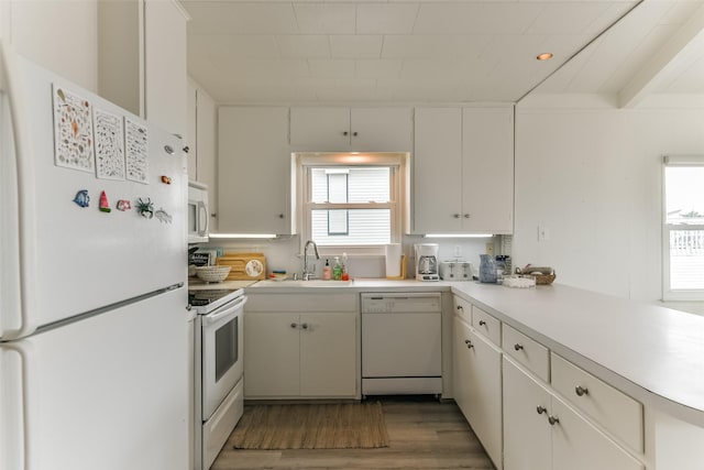 kitchen with white appliances, light wood finished floors, light countertops, white cabinetry, and a sink