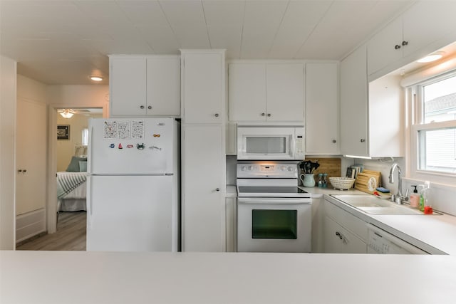 kitchen with light countertops, white appliances, a sink, and white cabinetry