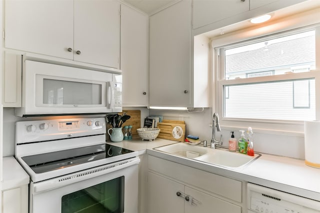 kitchen with white appliances, light countertops, a sink, and white cabinets