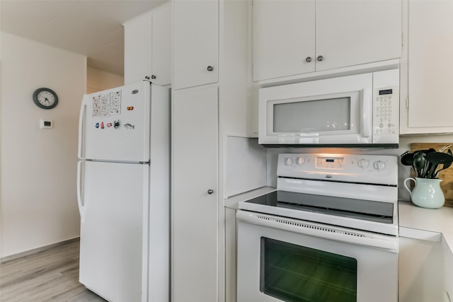 kitchen with white appliances, light countertops, light wood-style flooring, and white cabinetry