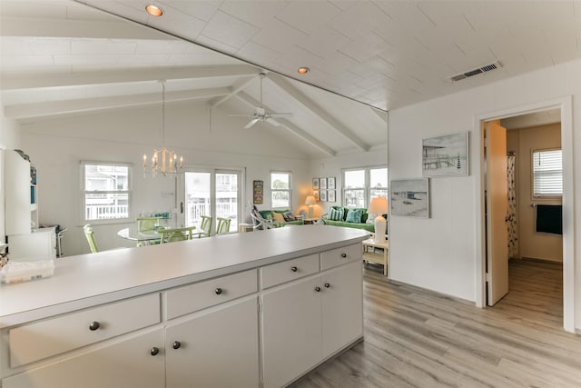 kitchen with vaulted ceiling with beams, light countertops, light wood finished floors, and white cabinetry