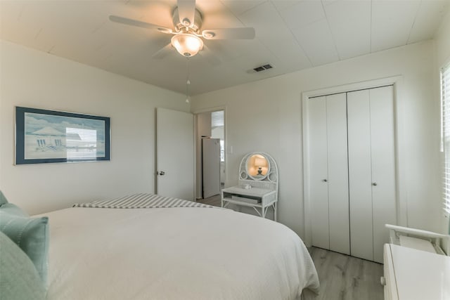 bedroom featuring light wood-type flooring, ceiling fan, visible vents, and a closet