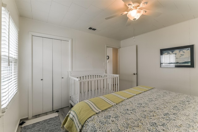 bedroom with ceiling fan, visible vents, a closet, and wood finished floors