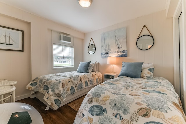 bedroom featuring dark wood-type flooring, a wall mounted AC, and baseboards