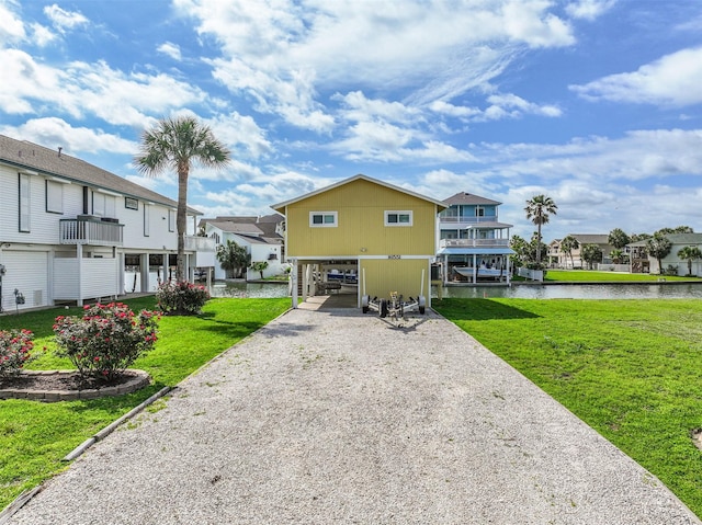 exterior space with a residential view, gravel driveway, a water view, a yard, and a carport