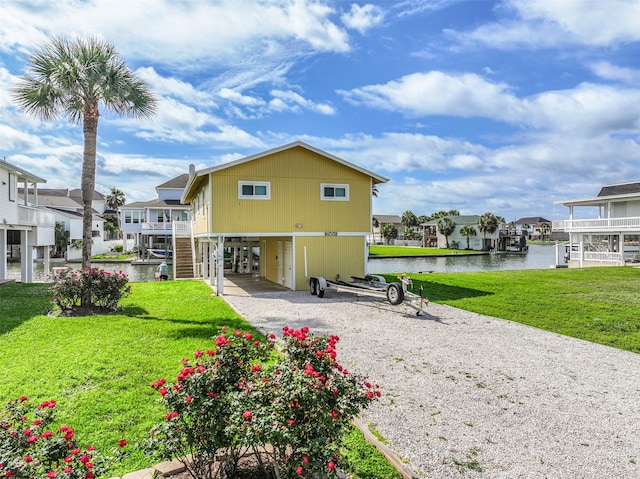 rear view of house featuring a water view, a residential view, a carport, and a yard