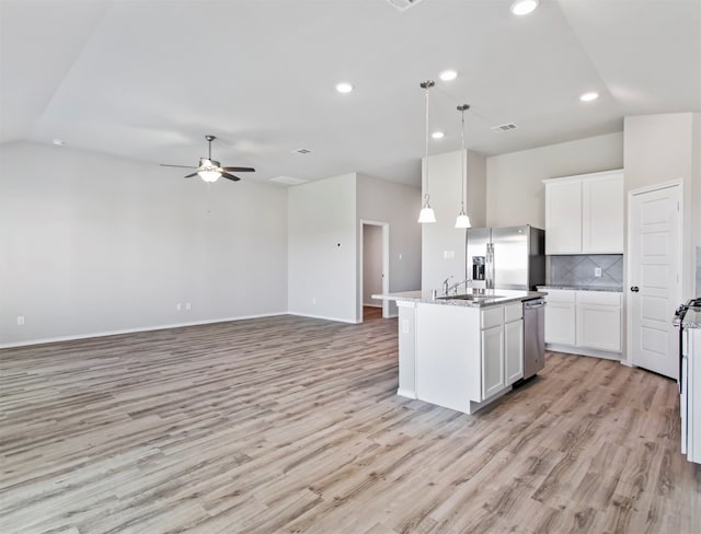 kitchen featuring backsplash, stainless steel appliances, light hardwood / wood-style floors, decorative light fixtures, and a kitchen island with sink