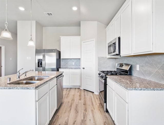 kitchen featuring decorative backsplash, light hardwood / wood-style flooring, pendant lighting, appliances with stainless steel finishes, and sink