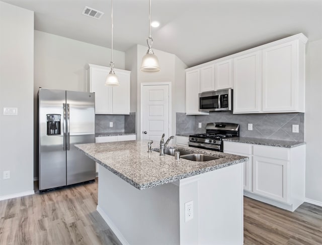 kitchen with appliances with stainless steel finishes, light hardwood / wood-style floors, decorative backsplash, and sink