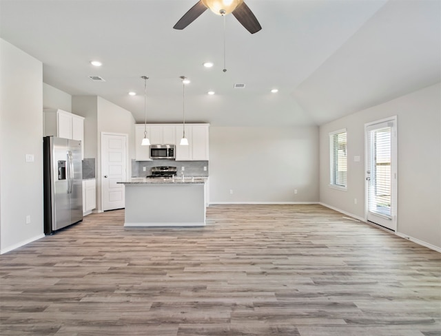 kitchen with light hardwood / wood-style floors, vaulted ceiling, white cabinetry, stainless steel appliances, and pendant lighting