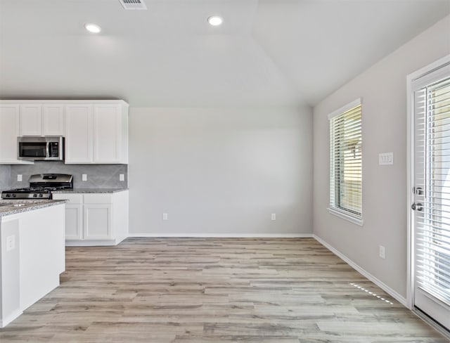 kitchen with stainless steel appliances, plenty of natural light, tasteful backsplash, and lofted ceiling