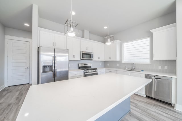 kitchen with appliances with stainless steel finishes, light hardwood / wood-style flooring, decorative backsplash, and pendant lighting