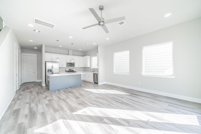 unfurnished living room with light wood-type flooring, sink, and ceiling fan