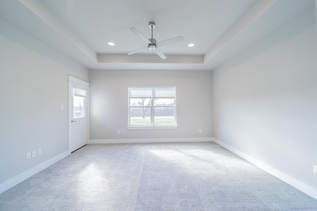 carpeted empty room featuring ceiling fan and a raised ceiling