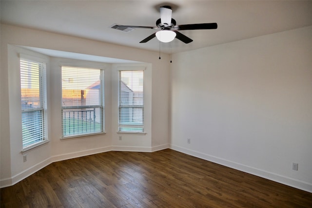 empty room featuring ceiling fan, plenty of natural light, and dark hardwood / wood-style flooring