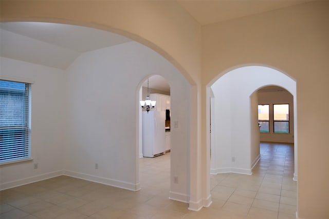 unfurnished room with light tile patterned flooring, a chandelier, and vaulted ceiling