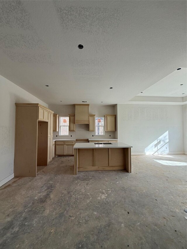 kitchen featuring light brown cabinetry, a kitchen island, and a textured ceiling