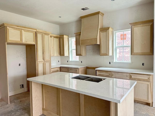 kitchen featuring black electric stovetop, a center island, custom range hood, and light brown cabinetry