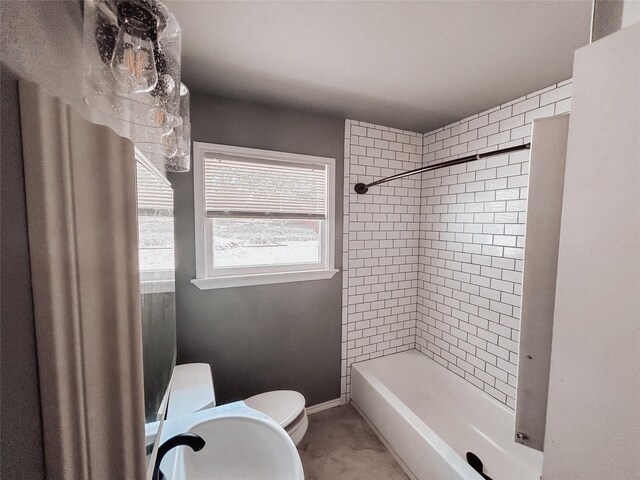 bathroom featuring tiled shower / bath and toilet