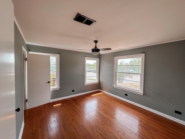 empty room with ceiling fan, ornamental molding, and wood-type flooring