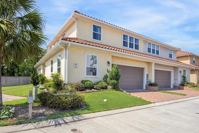 mediterranean / spanish home featuring stucco siding, decorative driveway, a front yard, and fence